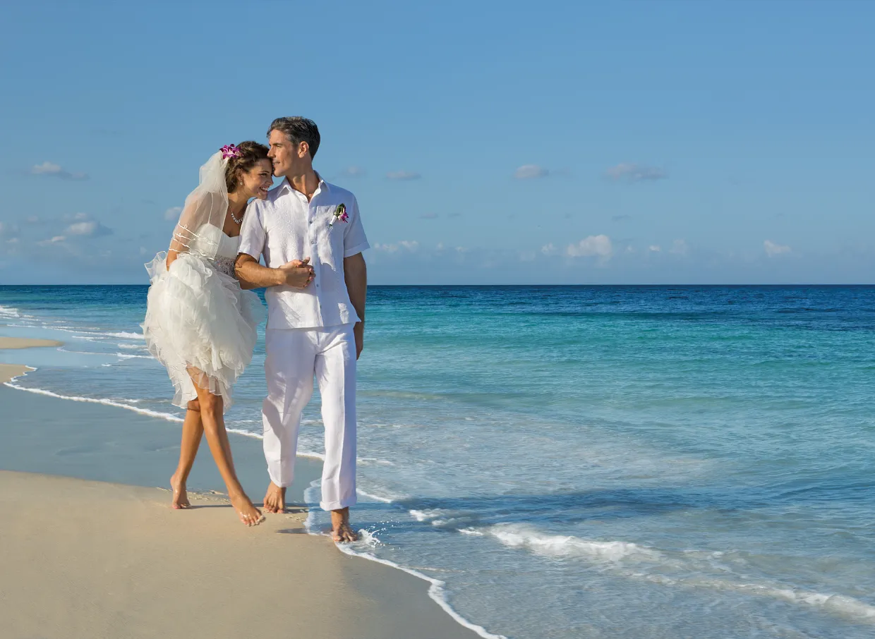 Couple walking on Caribbean beach — all-inclusive honeymoon packages with flights from Canada