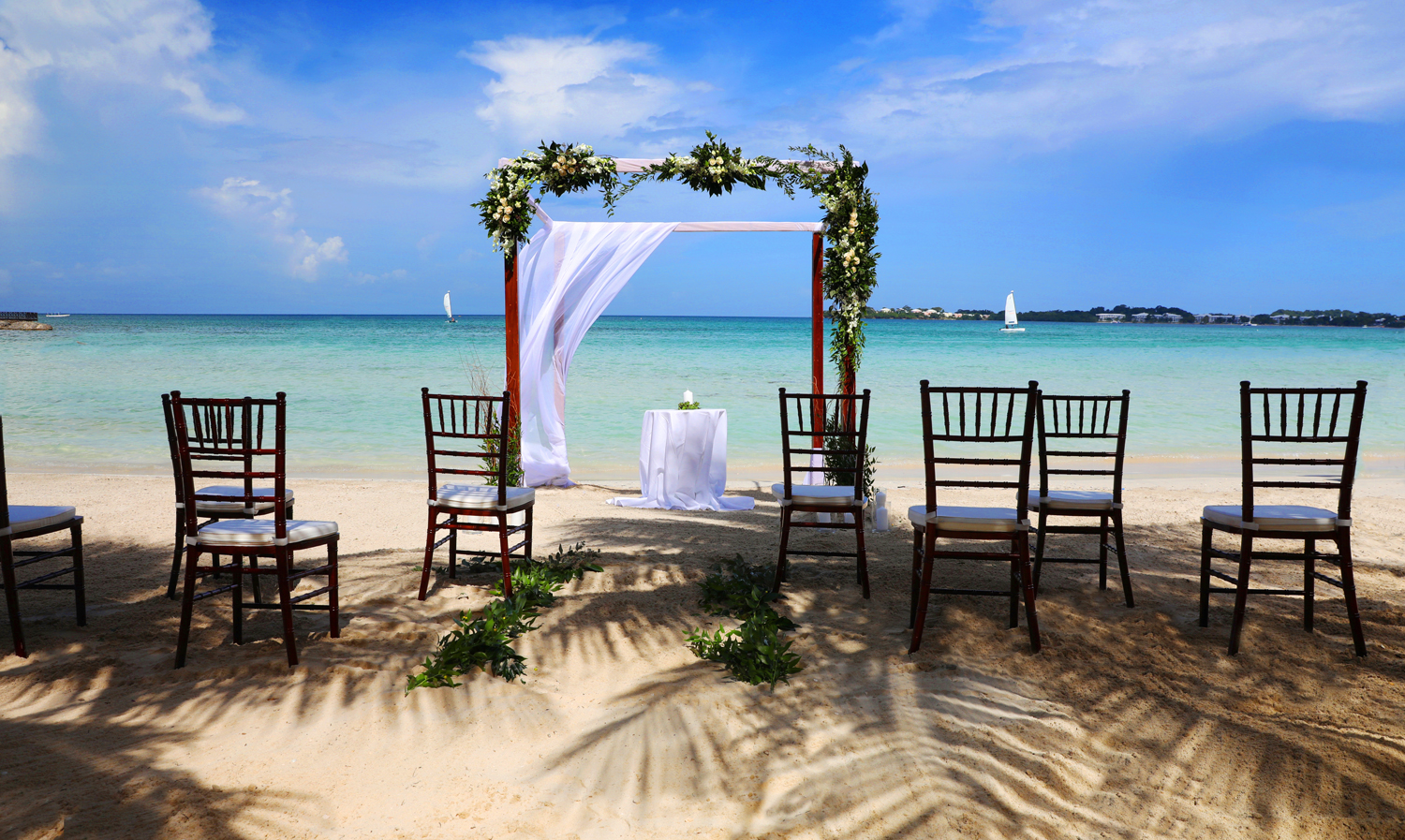 Jamaica wedding ceremony on white sand beach, shaded with palms with turquoise Caribbean waters